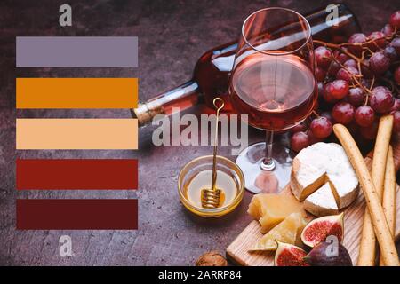 Bicchiere e bottiglia di vino gustoso con spuntini su sfondo colorato. Motivi di colore diversi Foto Stock