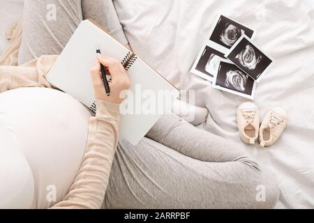 Donna incinta scrivere a-do-list, vista dall'alto, spazio libero Foto Stock