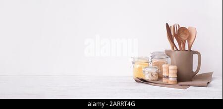 Set di utensili da cucina e groats sul tavolo vicino muro bianco con spazio per il testo Foto Stock