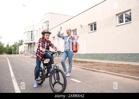 Madre orgogliosa di sua figlia che ha imparato a guidare la bicicletta all'aperto Foto Stock