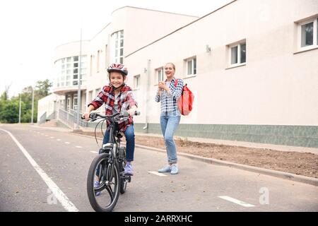 Madre orgogliosa di sua figlia che ha imparato a guidare la bicicletta all'aperto Foto Stock