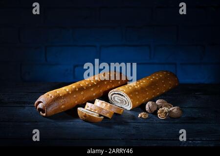 Pane dolce tedesco con noce su tavola di legno bruciato con sfondo di mattoni blu Foto Stock