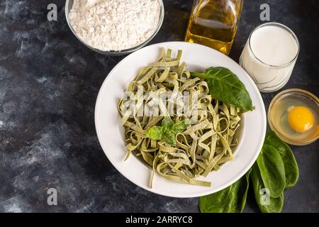 Pasta, verdure, erbe e spezie, olio d'oliva, ingredienti per la cucina italiana su sfondo scuro. Spazio di copia Foto Stock