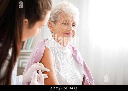 Medico dando donna diabetica iniezione di insulina a casa Foto Stock