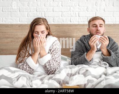 Giovane coppia malata a letto a casa Foto Stock