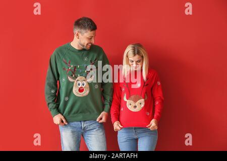 Coppia felice in maglioni di Natale su sfondo a colori Foto Stock