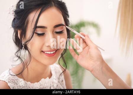 Trucco professionale artista che lavora con la giovane sposa asiatici a casa Foto Stock