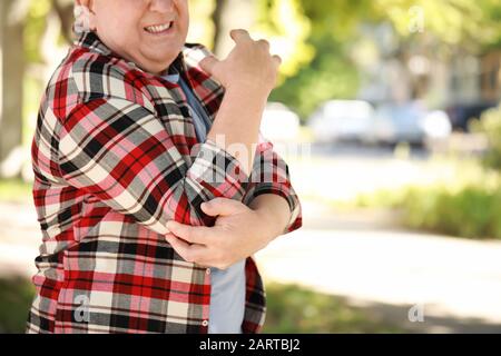 Uomo anziano che soffre di dolore in gomito all'aperto Foto Stock