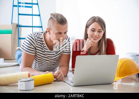 Felice coppia giovane con laptop riparazione di pianificazione nella loro nuova casa Foto Stock