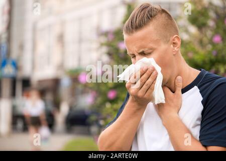 Giovane uomo che soffre di allergia all'aperto Foto Stock