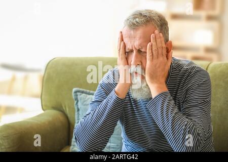 Senior l uomo che soffre di mal di testa a casa Foto Stock