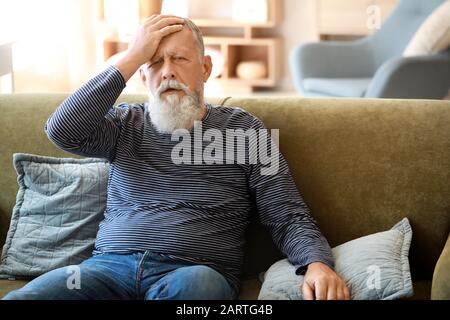 Senior l uomo che soffre di mal di testa a casa Foto Stock