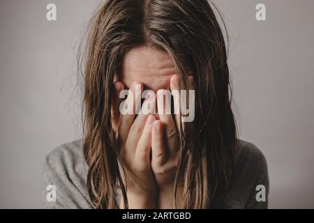 Donna copre il viso nelle mani. Concetto di disperazione, depressione, perdita o condizione mentale Foto Stock