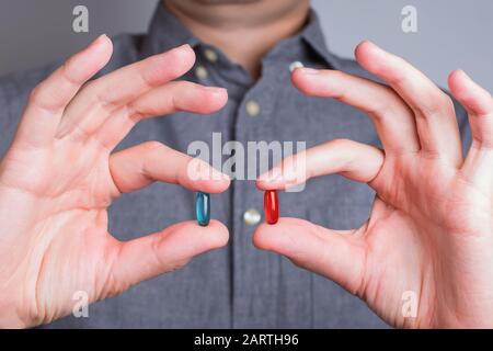 Mani dell'uomo primo piano con pillole rosse e blu Foto Stock