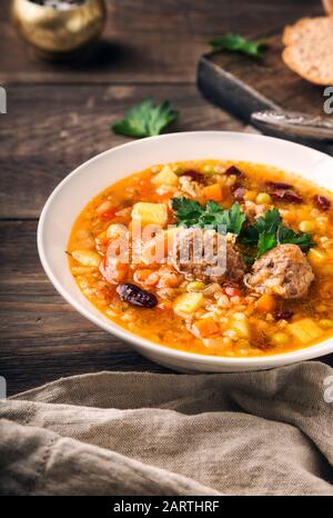 Zuppa di verdure fatta in casa con polpette e fette di pane su sfondo rustico in legno. Foto Stock