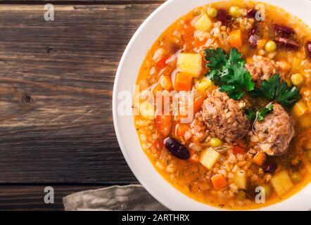 Zuppa di verdure fatta in casa con polpette e fette di pane su sfondo rustico in legno. Vista dall'alto. Primo piano. Foto Stock