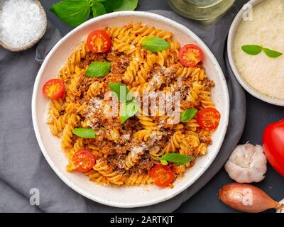 Pasta bolognese. Fusilli con salsa di pomodoro, carne macinata macinata, foglie di basilico. Cucina tradizionale italiana. Vista dall'alto Foto Stock