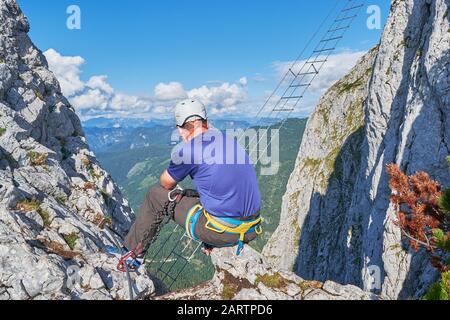 Uomo che guarda verso la scala ferrata di Intersport Klettersteig, vicino a Gosau, Austria. Foto Stock
