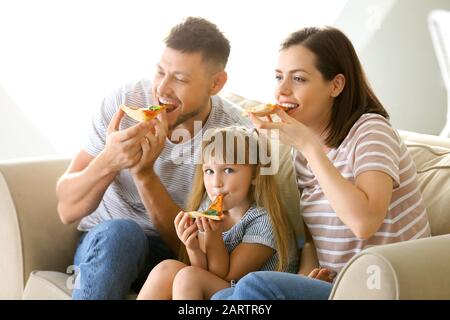 La famiglia felice di mangiare la pizza mentre si guarda il TV a casa Foto Stock