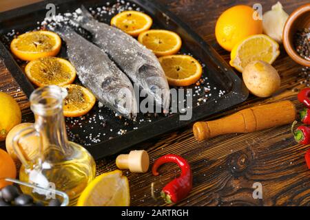 Vassoio con spigola fresca e ingredienti sul tavolo Foto Stock