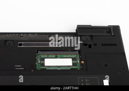 Primo piano del modulo di memoria del laptop sullo slot della scheda madre. Parte inferiore del notebook su sfondo bianco, il notebook è stato prodotto nel 2003. Foto Stock