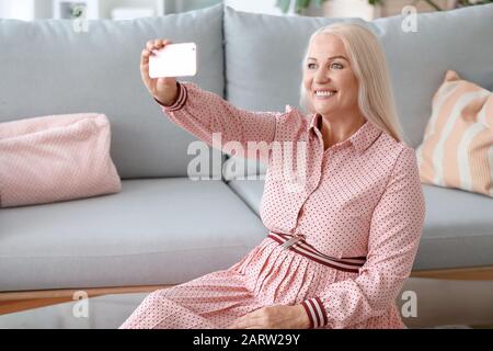 Donna matura positiva per il corpo che prende selfie a casa Foto Stock