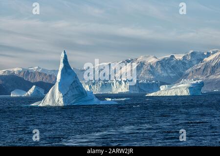 Alba in fiordo Scoresby Sund. Ghiaccioli galleggianti di fronte alle montagne innevate. Kangertitivaq, Groenlandia, Danimarca Foto Stock