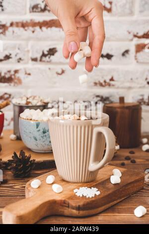 Marshmalling donna in tazza con cioccolata calda sul tavolo Foto Stock