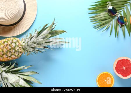 Composizione estiva con frutta tropicale, cappello e occhiali da sole su sfondo colorato Foto Stock