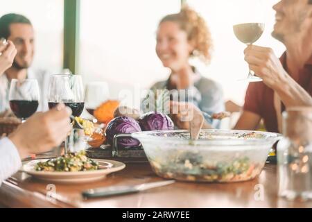 Amici felici mangiare cibo vegetariano e bere vino rosso - Vegan famiglia mangiare verdure fresche in agriturismo Foto Stock