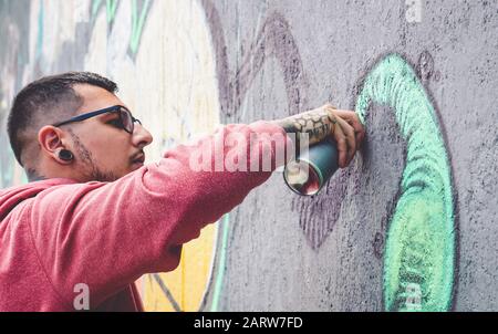Street graffiti pittura artista con uno spray colorato può murale graffiti sul muro della città - Urban e moderno Street art stile di vita concetto Foto Stock