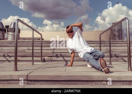 ballerino è giovane ragazzo, in estate in città, danza di strada, movimento di pausa, stile giovanile moderno. Moda e sport fitness. Spazio libero per copiare il testo Foto Stock