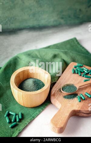 Composizione con polvere di spirulina e pillole sul tavolo Foto Stock