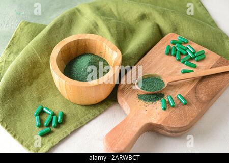 Composizione con polvere di spirulina e pillole sul tavolo Foto Stock