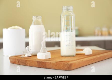 Bottiglie di latte per bambini con succhietto sul tavolo in cucina Foto Stock