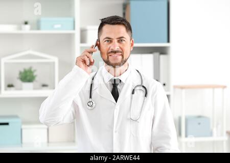 Ritratto di medico maschio che parla per telefono in clinica Foto Stock