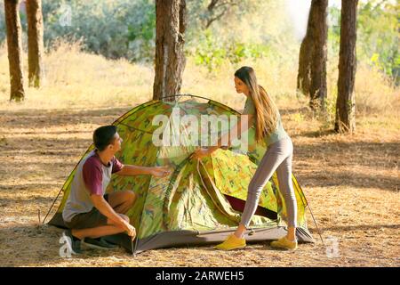 Amici che mettono in campeggio tenda nella foresta Foto Stock