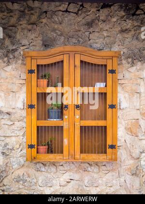 Armadietto cinese di legno appeso su una parete di cemento con fiore pentole in esso Foto Stock