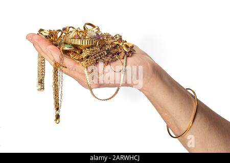 Colpo orizzontale della mano e del braccio di una donna che tiene un mucchio di gioielli in costume d’oro e indossa un braccialetto. Sfondo bianco con spazio di copia. Foto Stock