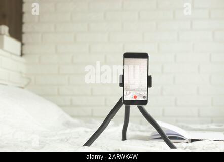 Lo smartphone si trova su un treppiede compatto a casa per la registrazione di video. Concetto di tecnologia blogging. Foto Stock