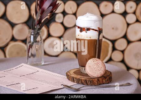 Bicchiere di gustoso caffè con frittella e menu sul tavolo nel caffè Foto Stock