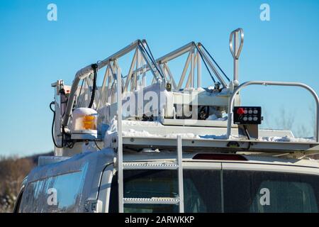 Una vista ravvicinata e dettagliata dell'attrezzatura operativa in cima a un furgone mobile, luce ambra e sollevamento a forbice sul dumper a benna. Sotto un cielo invernale blu Foto Stock