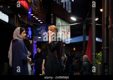 Le ragazze persiane passano il loro tempo libero per le strade di Teheran. I giovani ragazzi e ragazze iraniani di solito visitano i loro amici di fronte a un bar. Foto Stock