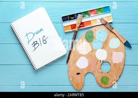 Notebook con testo SOGNO GRANDE e forniture di artisti su sfondo di legno Foto Stock