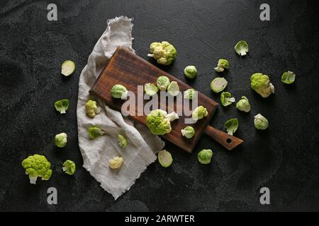 Tavola con cavolo fresco diverso su sfondo scuro Foto Stock