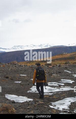 Immagine verticale di un escursionista con una fotocamera sul Colline coperte di neve in Islanda Foto Stock