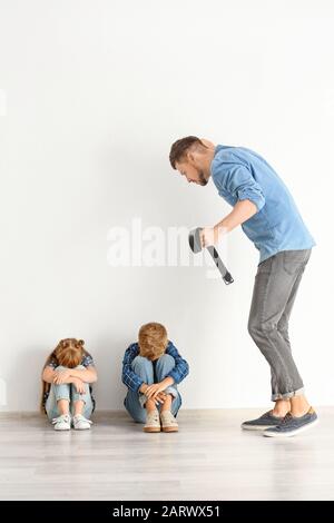 Uomo che minaccia i suoi bambini piccoli. Concetto di punizione fisica Foto Stock