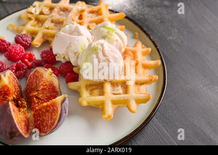 Piatto con gustosi waffle, frutti di bosco e fichi sul tavolo, primo piano Foto Stock