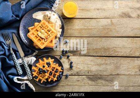 Piatti con gustosi waffle, frutti di bosco e gelato a tavola Foto Stock