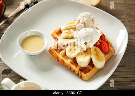 Gustosi waffle, gelato, frutta e salsa su piatto Foto Stock